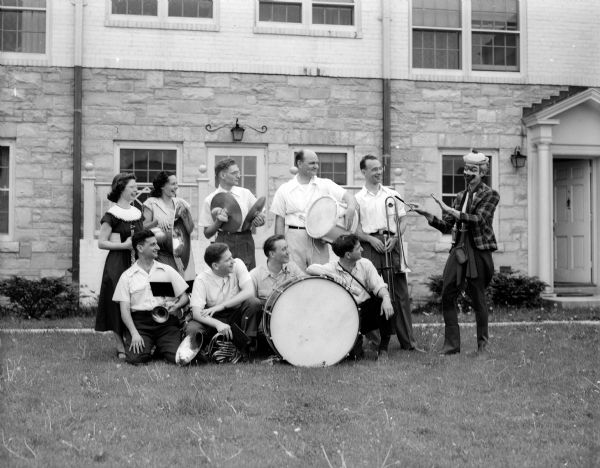 The University of Wisconsin faculty band led the parade of children of University of Wisconsin faculty living in University Houses at Eagle Heights march in a Memorial Day celebration.  Pictured kneeling in the front row left to right: Charles Heidelberger, Herman Holtzman, Virgil E. Johnson, and Don Voegeli. Standing in the back are left to right: Mrs. Virgil Johnson, Mrs. Franklyn Bright, Julius Weinberg, Ralph Huitt, Mr.Bright, and Professor Luckhardt of the university music school who led the band dressed as a clown.