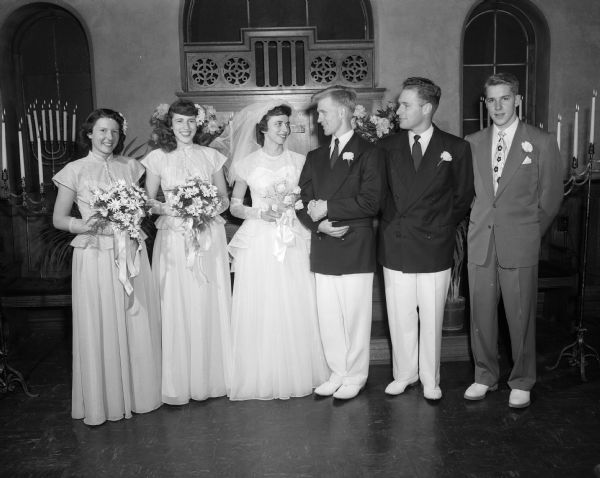 Group portrait of a wedding party standing in front of altar in Hunt Chapel of Christ Presbyterian Church.  Pictured left to right are: Jo Anne Elmer, bridesmaid; Martha Dobbs, Maid of Honor; Ada Mae Dobbs, bride; John L. Iltis, groom; Charles Iltis, Best Man; Ted Iltis, usher.