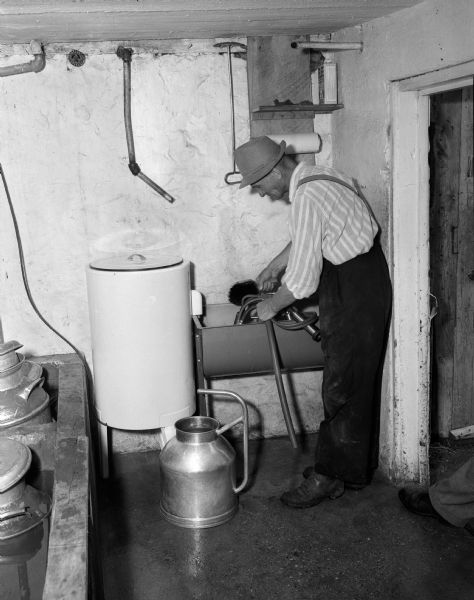 World War II war relief services.  Man washing milking equipment.