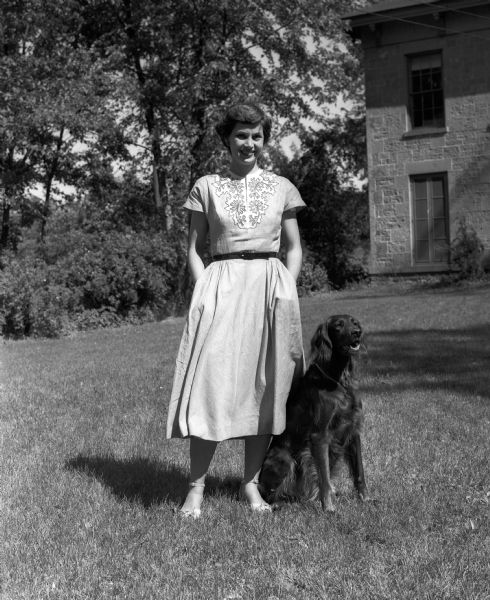 Alice Darling of 1224 Spaight Street, Chairman of the Badger Kennel Club Dog Show, is shown with her Irish Setter, Erin. In the background is a 1860's era stone house.