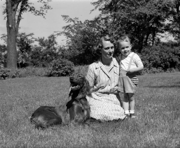 Virginia Spence, active member of the Badger Kennel Club, sitting outdoors with her Irish Setter, Corky, and her son, 2 1/2-year-old Dusty.