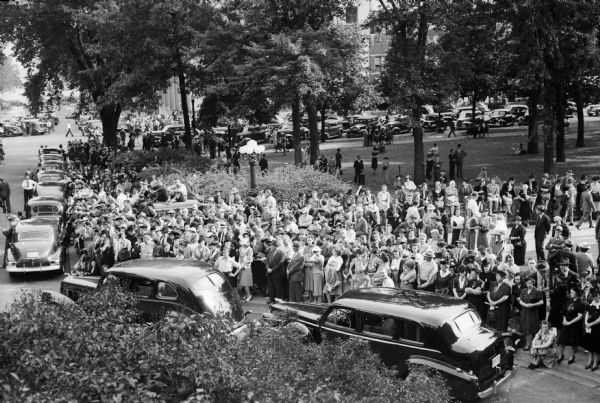Elevated view of the overflow crowd standing outside the Wisconsin State Capitol during the funerals for University of Wisconsin president Glenn Frank and his son Glenn, Jr. The father and son died September 15, 1940 in an automobile accident south of Green Bay while campaigning for the Republican nomination for the United States Senate.
