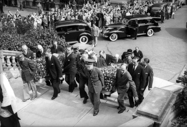 The caskets of University of Wisconsin president Glenn Frank and his son Glenn, Jr. are carried up the steps of the Monona Avenue entrance to the Wisconsin State Capitol for the state funeral services. The father and son died September 15, 1940 in an automobile accident south of Green Bay while campaigning for the Republican nomination for the United States Senate.  On the left, carrying the casket of Glenn, Jr. are Fred J. Curran, Lawrence H. Fitzpatrick, Fred Graff, Harold E. McClelland, Richard Keeley, and Ralph Beck. Bearing Dr. Frank's casket on the right are Dr. Karver Puestow, Fred Holmes, Dean Chris L. Christensen, J. Ward Rector, Don Anderson, and Dr. Gunnar Gunderson.