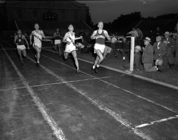LeRoy "Luke" Collins (right), University of Wisconsin's quarter-miler, is shown as he wins the Big Ten-Pacific Coast track meet at Camp Randall Stadium. Also pictured is Franklin "Pitch" Johnson (center), Stanford University, who finished in second place, and close behind him, at left, is the third place winner, Wilbur Taylor, also of Stanford.