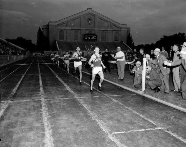 University of Wisconsin's Don Gehrmann (right), wins the half mile race in the Big Ten-Pacific Coast intercollegiate track meet held at Camp Randall Stadium in a record breaking one minute and 56 seconds. Also shown (center) is Bob Chambers of Southern California University coming in at second place.
