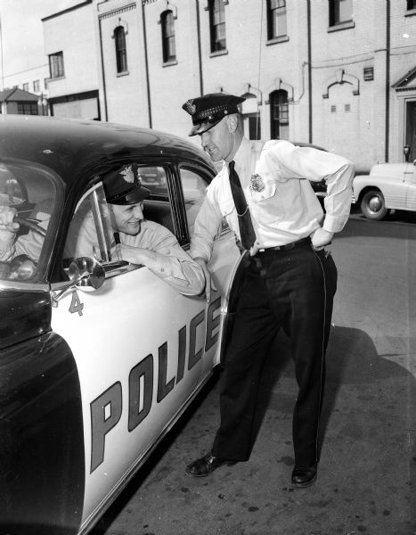 Patrolman Norman "Red" Ehle (right), in charge of the patrol car changeover, talks to driver Dom Schiro about how his car handles. A complete fleet of 20 new Chevrolet cars has been ordered from Hull's Capital Garage, which provided the low bid.
