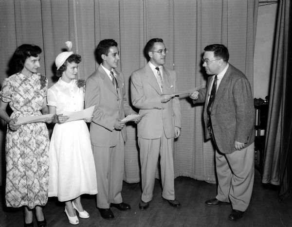 University of Wisconsin Professor Gian Orsini (right), is shown presenting UNICO scholarships to three Madison high school students and one from Hurley at a banquet of UNICO National Sunday. Receiving the awards are, left to right: Patricia Varnetti, Hurley; Patricia Jones, Madison Central; Joseph Balsamo, St. Joseph's; and Santo J. Caravello, Central.