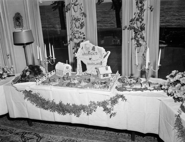 Front view of the buffet table at the Governor's residence set up to welcome a group of nationally-known travel editors to Wisconsin. Shown is a close-up of a "America's Dairyland" farm scene set up on the buffet table.