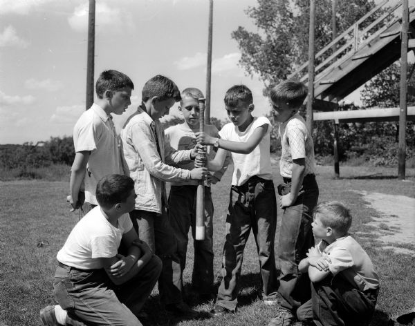 A group of boys prepares to choose sides for a baseball game at Hoyt Park. Clockwise from lower left are: Phillip Brown, Dennis Timm, Bobby Meyer, Terry Kinney, Jerry Kauffman, Lonny Schepp, and Jackie Church.