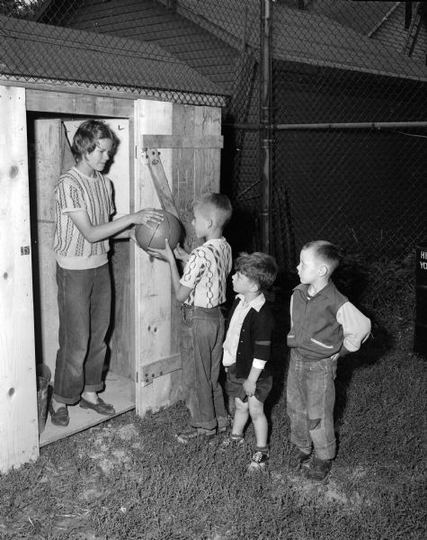 Frances Niles hands out a ball to three boys at the Milton-Charter park playgound. The boys are, left to right: Ross Parisi, Don Brashi, and Marvin Bloom.