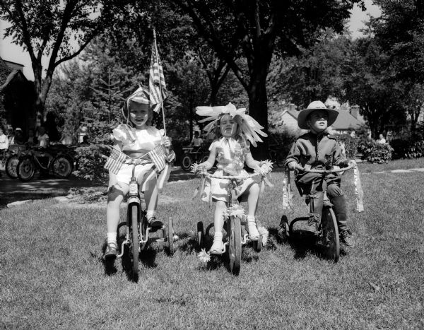 Mary Elolen Statz, Mary Jo Pankow, and Chester Rideout pose for a portrait in costume on their decorated bikes.