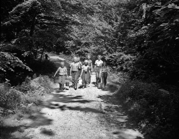 Girl Scouts carry water up a hill to their camp site at Camp Greenwood, a day camp at Picnic Point for Intermediate Girl Scouts between the ages of 10 and 14.