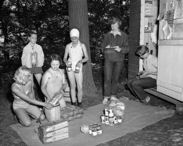 Girl Scouts at Camp Greenwood, a day camp at Picnic Point for Intermediate Girl Scouts between the ages of 10 and 14, gather the food they have helped contribute and which they will cook. Pictured from left to right are scouts: Julie Balts, Kathy Fleury, Jo Anna Cox, and Joanne Zurfluh, and camp program aides: Libby Brimmer and Ann Winn.