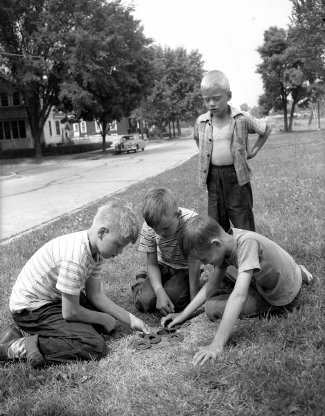 Three boys playing a game of "washers" at the Olbrich park playground, one of the thirty parks included in the summer playground program sponsored by the Board of Education Recreation Division. Pictured left to right are: Ronald Staver, Donald Struckmeyer, and Curtis Amble.