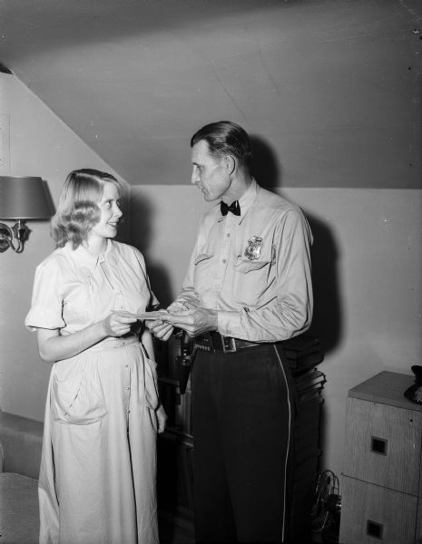 Mrs. Robert S. Lincoln, 3118 Buena Vista Street, receives an award from police officer Lester Shore for her "heroine efforts" in saving 3-year-old Kurt Wise, 1562 Jenifer Street, from drowning in the Yahara River. Mrs. Lincoln was an expectant mother on April 25 when she plunged into the Yahara River where it enters Lake Monona and saved Kurt.