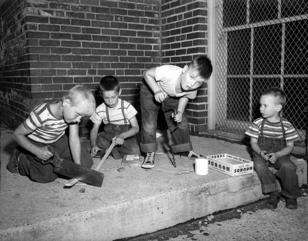 Pictured left to right are Jerry Licari, Henry Cuccia, and Tommy McCarthy, who are  building a birdhouse at the Longfellow playground. At far right is Henry's younger brother, George Cuccia, who is lending a little advice to the other boys. Carpentry projects are part of the summer program  sponsored by the board of education recreation division at thirty city playgrounds.