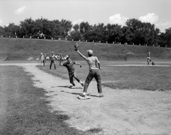 Boys play baseball at the Franklin School playground. The activity is part of the summer program sponsored by the board of education recreational division at thirty city playgrounds.