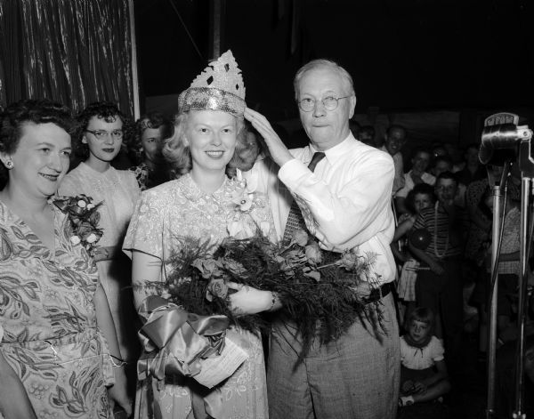 Mildred Rand is crowned "East Side Merchandise Queen" by City Councilman Herbert C. Schenk at the annual festival of the East Side Business Men's Association.