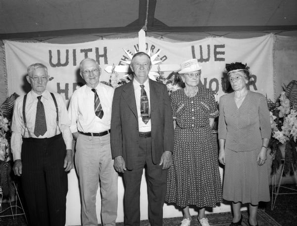 The five surviving charter members of Zion Lutheran Church, 247 Division Street, stand in front of a banner at the picnic celebrating the church's 50th anniversary. From left are: Henry C. Kracht, William Fahning, Henry Wiese, Mrs. Albert Wiese, and Mrs. C.B. Fritz.