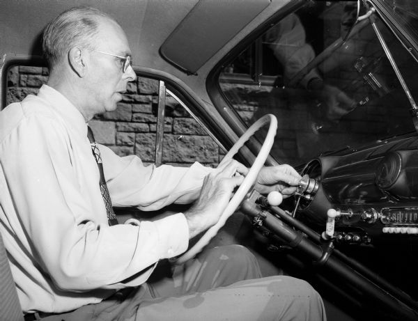 Mr. R.G. Reynoldson of 150 Lakewood Boulevard is pictured behind the wheel of his car demonstrating his invention, the "aeromatic speed control." Mr. Reynoldson, a planning engineer at Oscar Mayer Company, built and patented the device which changes the maximum speed merely by flipping a pointer on the speedometer.