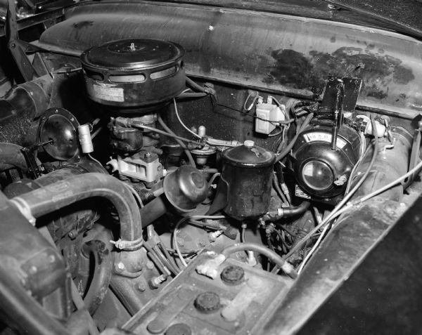 The speed control device invented by R.G. Reynoldson of 150 Lakewood Boulevard is shown attached to a second speedometer under the hood of his car. The "aeromatic speed control" was built and patented by Mr. Reynoldson, a planning engineer at Oscar Mayer Company. The device changes the maximum speed merely by flipping a pointer on the speedometer.