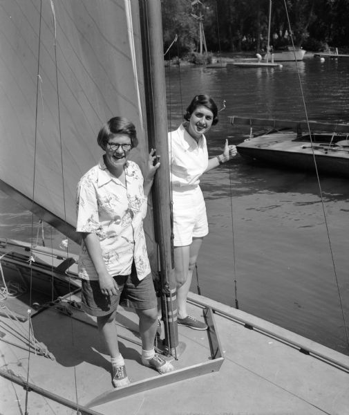 Two Madison teenagers, Judith Rendall and Gina Johnson, standing on board Judy's Class C sailboat "Nite-Hawk."