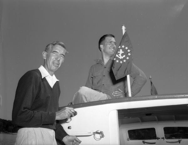 Morgan E. Manchester, Maple Bluff, commodore of the Mendota Yacht Club and general chairman of the Inland Lakes Regatta, posing with his son aboard the family's cruiser, "Menace."