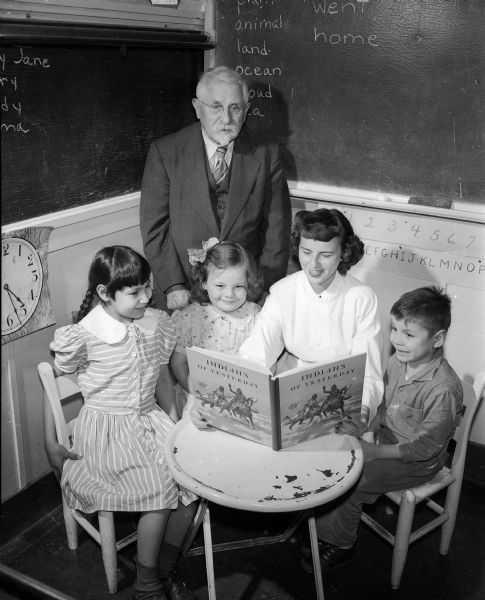 Three children patients at the Morningside Tuberculosis Sanitorium, 300 Femrite Drive, are pictured with their teacher, Murva James (center), and Dr. W.D. Frost, executive director of the facility (standing), in the new children's library made possible by a grant from the Roundy's Fun Fund.