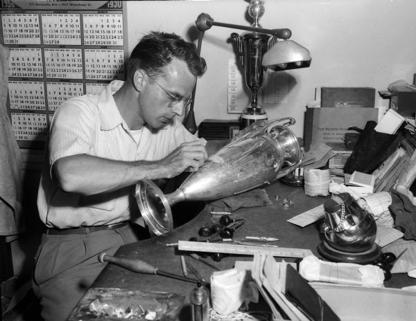 Paul Hennie, wholesale metal engraver, working on a large trophy in his office at 23 North Pickney Street.