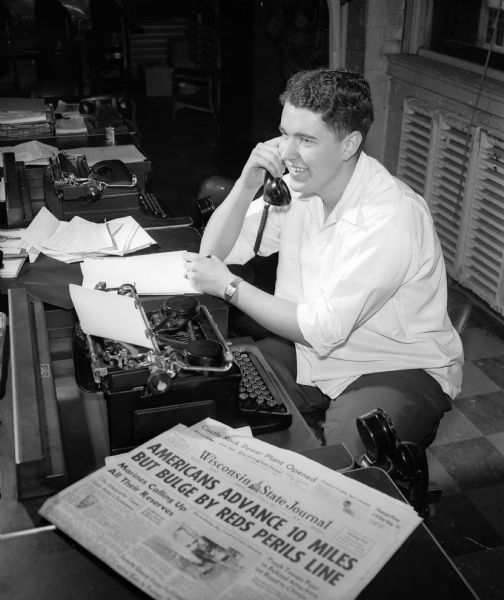 Jack Harned, 1950 West High School graduate, uses a telephone and typewriter at his summer job as a reporter at the <i>Wisconsin State Journal</i>.