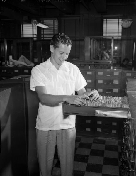 Leon Rosenberg, West High School 1950 graduate and valedictorian, is shown at his summer job at the <i>Wisconsin State Journal</i> filing hundreds of engravings and clippings in the "morgue" or library.