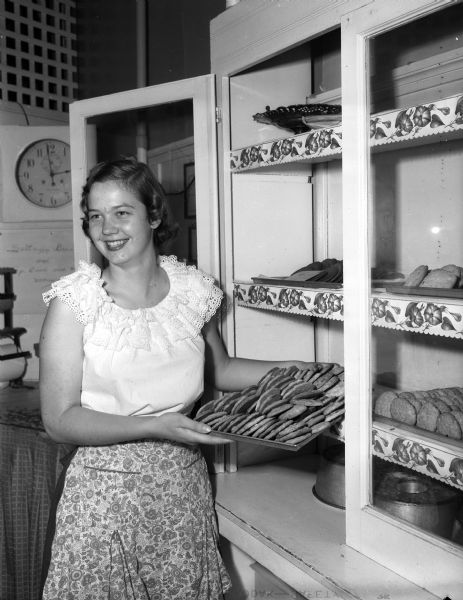 Peggy Huiskamp, soon to be a Wisconsin High School senior, holds a tray of cookies at her summer job at Langdon's Home Bakery and Delicatessen on State Street.