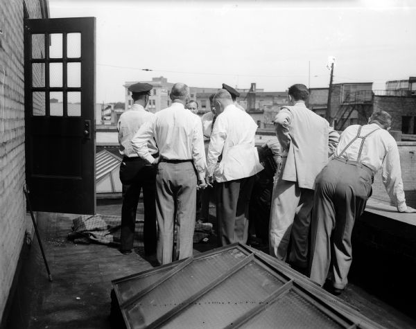 Police officers and company employees stand on the roof of the Wisconsin Power and Light Building, 122 West Washington Avenue, where M.C. Alexander of 303 Lathrop Street, took his own life by jumping from an eighth-floor window of the building. A suicide note indicated that Mr. Alexander, an employee of Wisconsin Power and Light and a veteran of World War II, was despondent due to poor health.