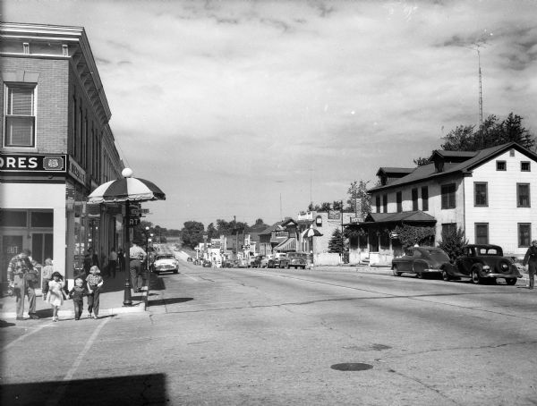 View of Main Street showing stores, people and vehicles.