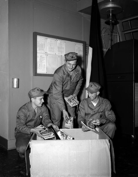 Three Marine reservists check over reading materials for their trip to the West Coast for active duty. They are: Pfc. D.K. Cartter, 1817 Kendall Avenue,Corporal A.H. Franz, 126 Proudfit Street, and Corporal C.M. Brager, Lodi.