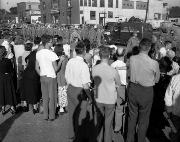 A crowd gathers to watch the Madison marine reserve unit marching down West Washington Avenue to board a train for duty in Korea.