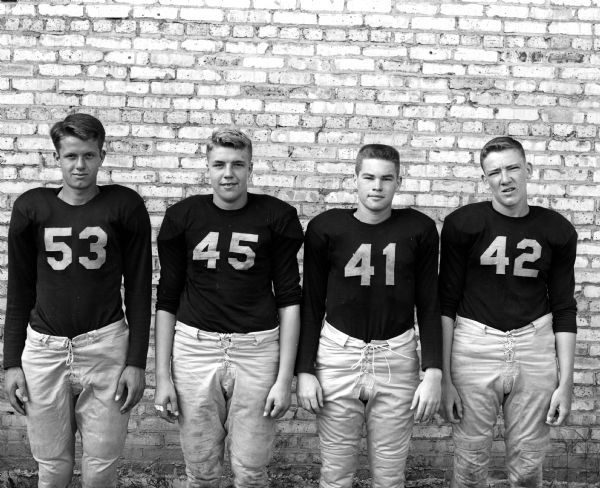 Group portrait of four Edgewood High School football players in uniform. Shown (L-R) are Pete Beyer, Soph. (#53); John Ace, Soph. (#45); Don Hanaway, Junior (#41); and Ken Corcoran, Junior (#42).