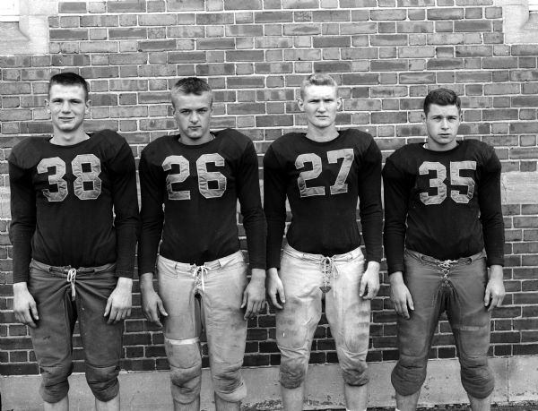 Group portrait of four unidentified East High School football players in uniform.