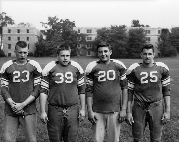 Four Wisconsin High School football players pose in uniform. They include #23 Steve Gerhardt, #39 Jim Black, #20 M. Phillips, and #25 Don Lehman.