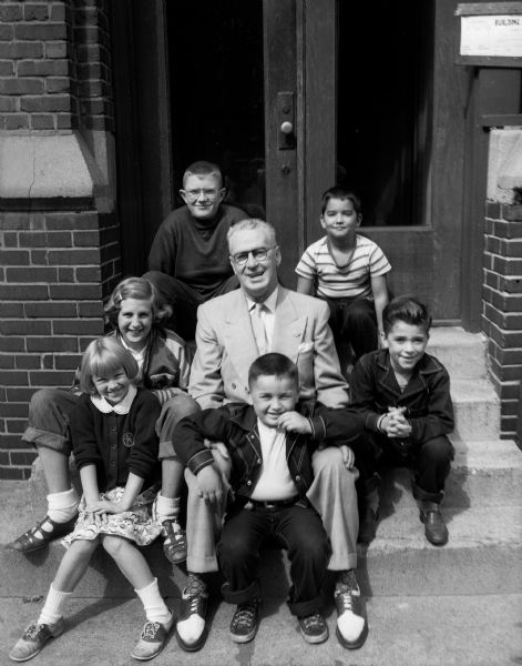 "Roundy" Coughlin sitting on a stoop with some neighborhood children who put on a magic show to collect money for Roundy's Fun Fund for handicapped kids.