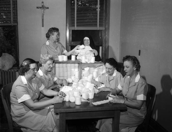 The making of bandages is another hospital necessity which can be taken over by volunteer workers. Sister M. Carmelita, superintendent of S. Mary's hospital, appears to be completely pleased with the efforts of the auxiliary members.
From left to right, the auxiliary workers are: Mrs. Edward (Helen) Donagan, Mrs. M.V. (Loretto) Crowley, Mrs. Irvin (Alma) Haas, Mrs. Charles F. (Eva) Schimel, Mrs. Leo (Irene) Blied.