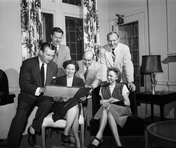 Members of the dance committee make arrangements for the kickoff football dance to be held at the University Club after the Wisconsin-Marquette game. In the front row are Professor Robert J. Francis, Mrs. Arthur P. (Julia) Miles, and Mrs. Arthur (Betty) Robinson. The men in the background are Professor Russell J. Hosler, Leslie J. Meinhardt, and Richard E. Sullivan.