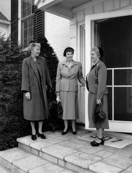 Three members of the Madison Civic Music Association board standing near a building entrance. They are: Helen Marting Supernaw, Mrs. Donald W. (Florence) Anderson, and Mrs. Mark (Beatrice) Goldberg.