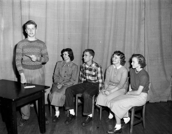 Five members of the student speakers' bureau for the United Givers' Fund posing for a group portrait. Speaking at right: Peter Noer, West High School. Seated, right to left: Sylia Sachtjen, East High; Leo Link, Edgewood High;  Darlene Gillette, Central High; and Lois Brustman, Wisconsin High.
