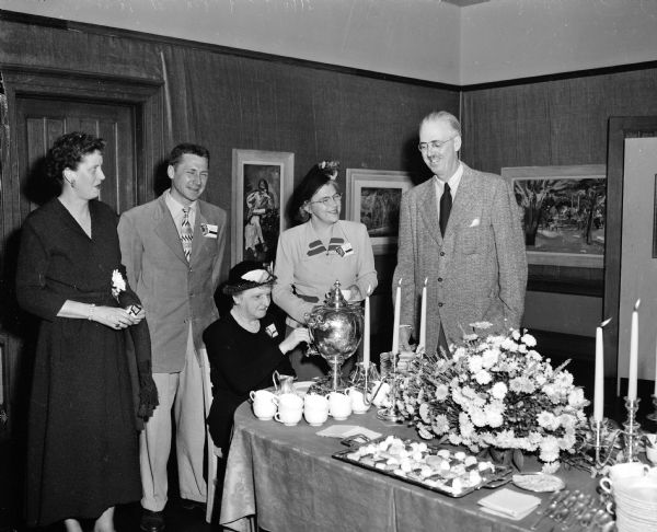 Members of the Madison Art Association celebrate the organization's 50th year with a tea and exhibition preview. Left to right, around the tea table are: Mrs. Francis Chapin, Chicago; Frederick Carpenter, chairman of the gallery committee; Mrs. Edwin (Rosa) Fred, pouring tea; Mrs. Theodore Wisniewski, in charge of floral arrangements; and Francis Chapin, artist, Chicago.