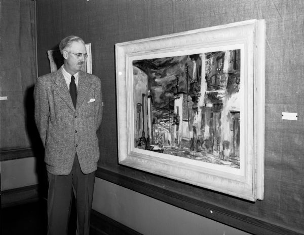 Artist Francis Chapin is shown standing beside his oil painting "House of Dogs, Mexico" which the Madison Art Association displayed at the Madison Free Library. The show included several other paintings done by the Chicago-area artist.