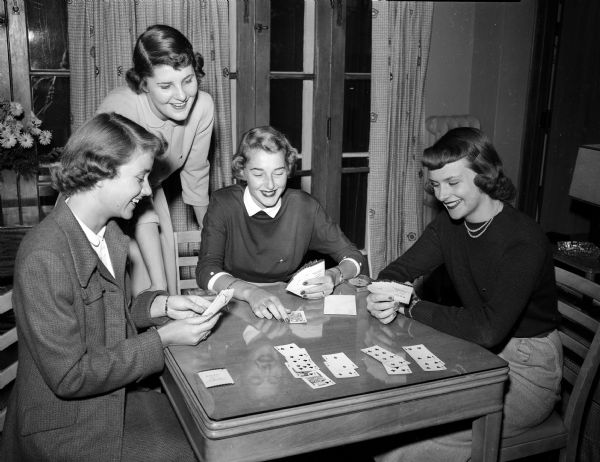 Four Madison pledges of the Kappa Alpha Theta sorority play bridge on a card table. From left are Margaret Mortens, Patricia Clardy, Mary Ann Pohle, and Marforie Lund.