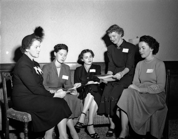 Group portrait of wives of new University of Wisconsin faculty members and members of the University League, Junior Division at the League's opening reception. Left to right: Mrs. Leslie (Dora) Osborn, 4217 Wanetah Trail; Mrs. Chester Harris, University Houses, membership chair; Mrs. Delbert H. Fulkerson (?), 1208 Erin Street; Mrs. Thompson (Diana) Webb Jr., 4210 Yuma Drive, president of the junior division; and Mrs. Charles (Margaret Higbie, 818 Maple Terrace. The husbands of Mrs. Osborn, Fulkerson, and Hibgie are new faculty members.