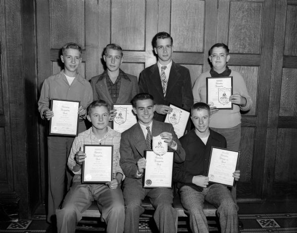 Group portrait of the Wisconsin State Journal's outstanding Madison newspaper boys who received their shoulder patch and scroll awards for meeting the high and exacting standards for service set by the Inland Press, Inc.for Midwest newspapers and awarded to only 1,100 out of half a million carriers. First row left to right: Arnold Pederson, Fred Smith, and Bill Buellesbach. Second row left to right: Richard Hilden, Bill Farrell, Ken Gelhaus, and Tom Tewes. Ten other Journal newspaper  boys in outlying communities also received awards.