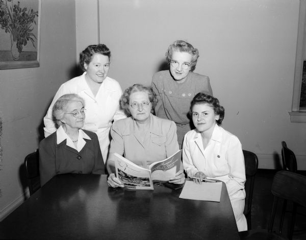 Looking over the program for the 33rd annual meeting of the American Dietetic Association, held in Washington D.C., are these Madison dietitians and teachers: 
seated, from left to right: Professor Helen T. Parsons, Professor May Reynolds, and Miss Adele Anderson of Wisconsin General Hospital.  Standing are Miss Ruth Dickie, chief dietitian at Wisconsin General Hospital, and Miss Doris Johnson, fellow in home economics at the University of Wisconsin.  With the exception of Professor Parsons, all of the women are attending the convention.
